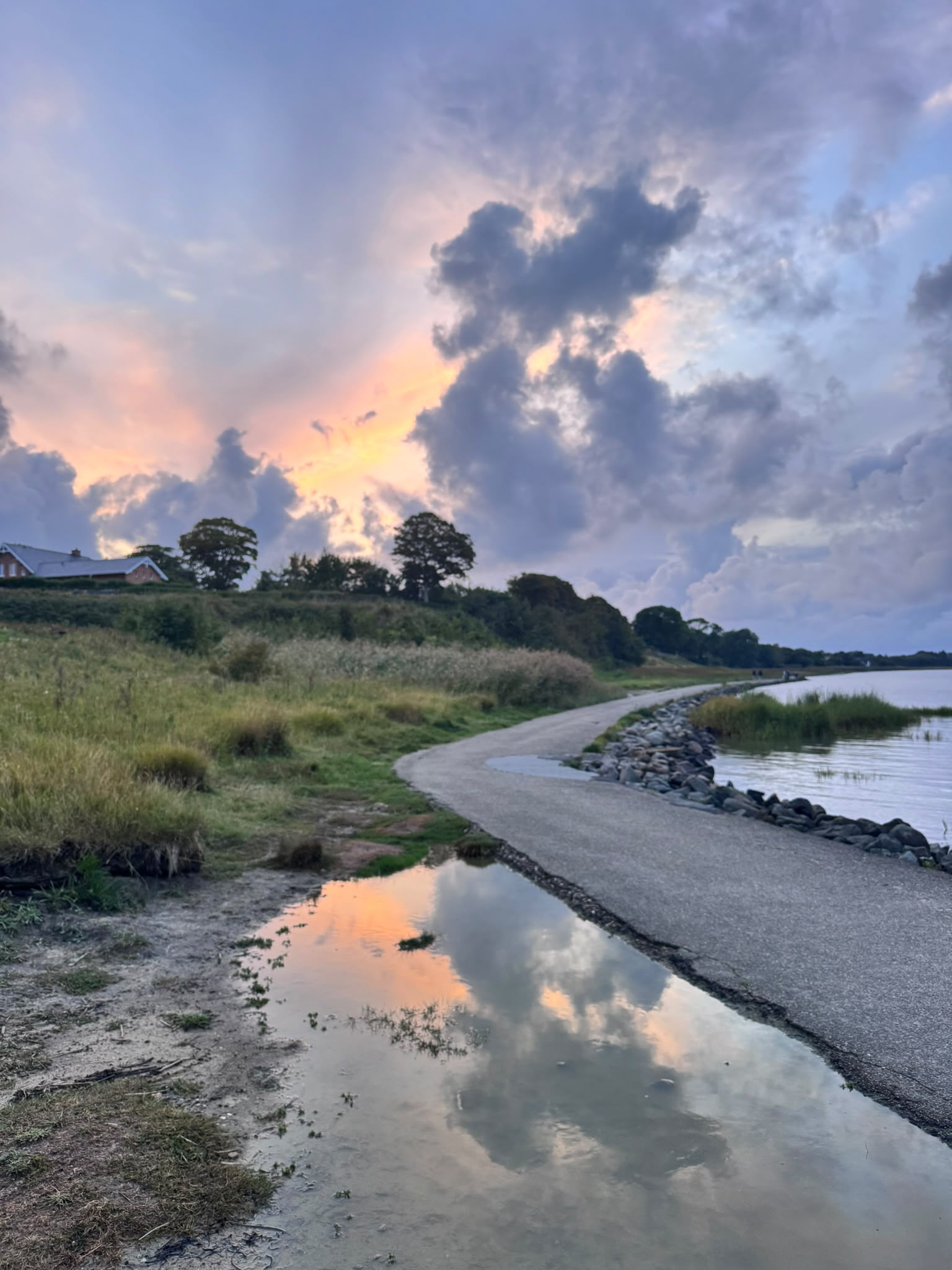 A reflective path beside the water beneath an open sky